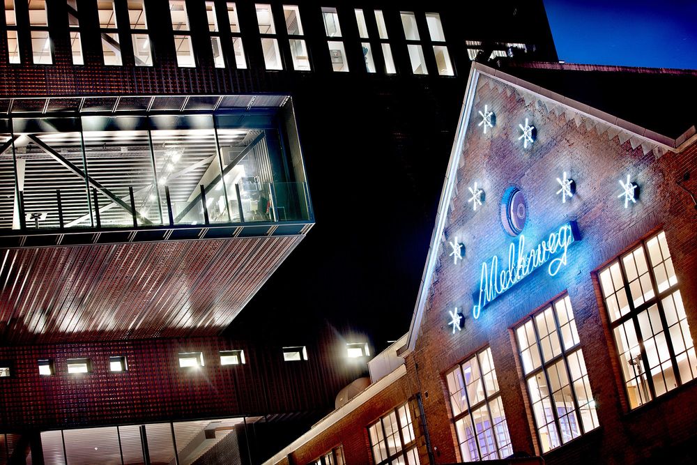 Facade of Melkweg building at night with Melkweg and stars neon signs