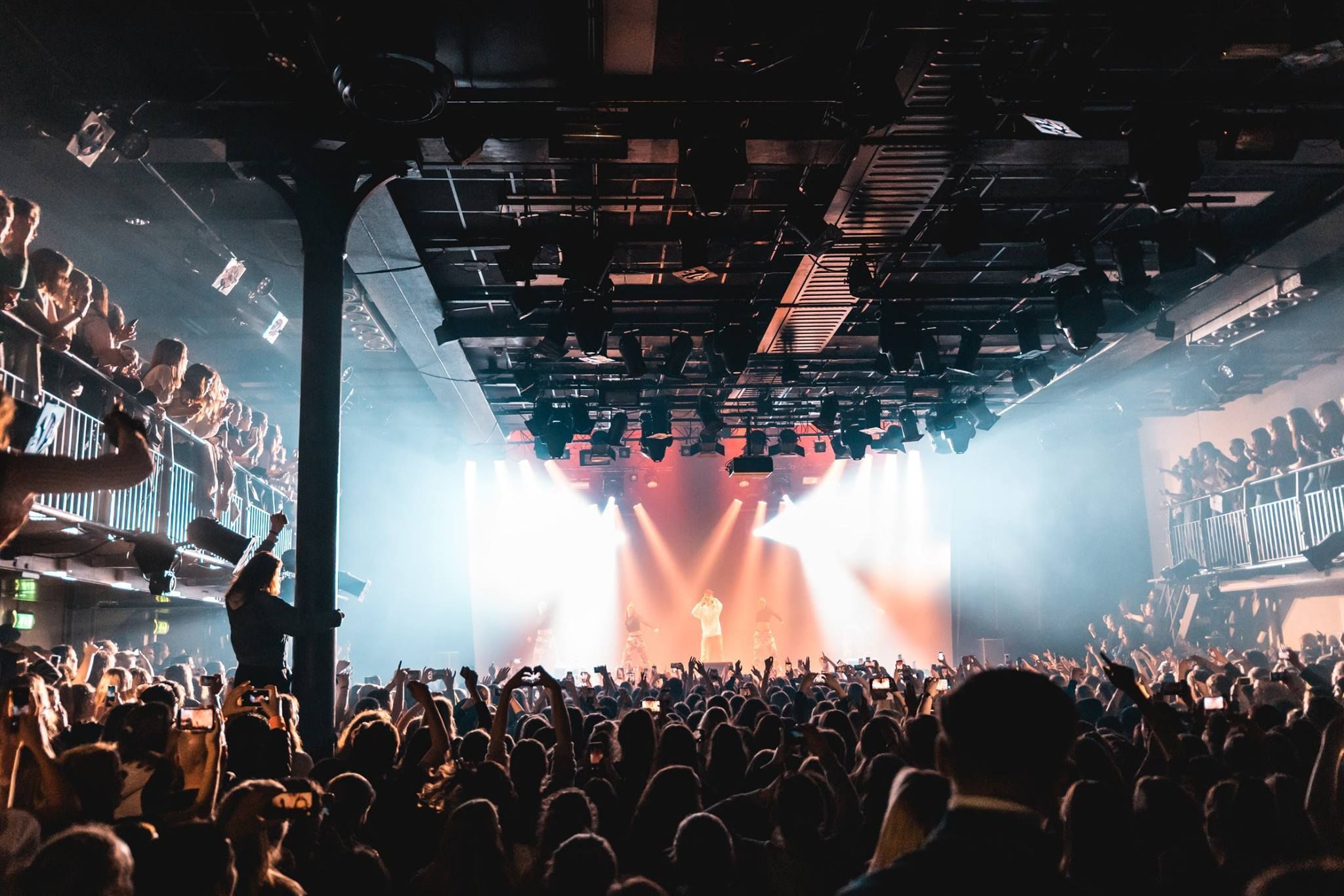 A dancing crowd within the Melkweg with a single singer on the stage.